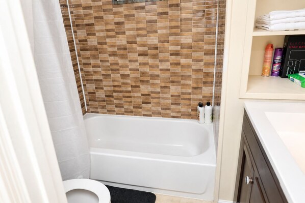 A bathroom with a bathtub, a toilet, and a shower area. - Modern DC Basement WiFi - Free Parking (Washington)