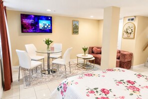 A hotel room with a bed, a round table with chairs, a sofa, a TV on the wall, and a painting. - Modern DC Basement WiFi - Free Parking (Washington)