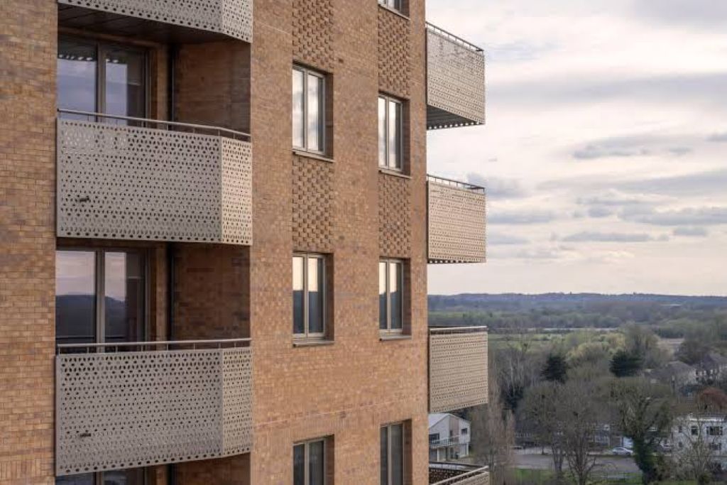 A multi-story building with balconies, large windows, and a view of a landscape.