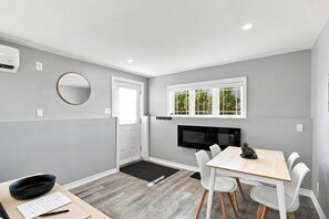 A modern kitchen with a built-in microwave, a dining area with a table and chairs, and a door leading to another room.