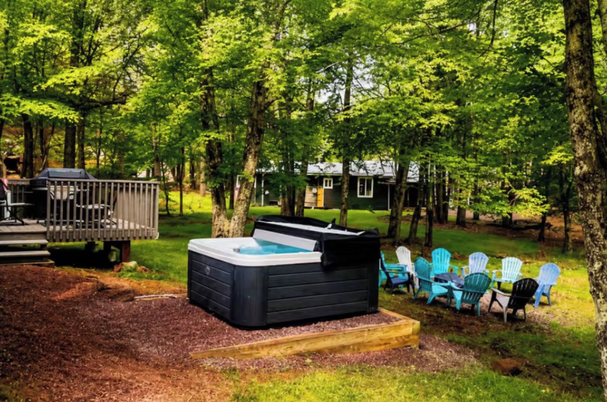 A hot tub surrounded by outdoor chairs and a deck.