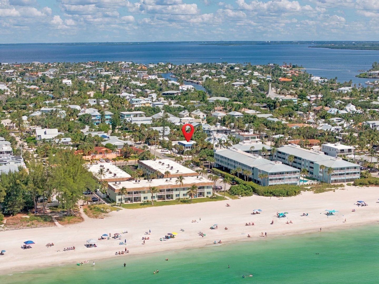 A coastal town with a beach, residential buildings, and a hotel with a pool.