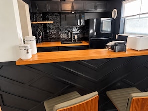 A modern kitchen with a black backsplash, stainless steel appliances, and a wooden countertop. - Updated 2BR Extended Stay with Parking and On-Site Laundry (Cincinnati)