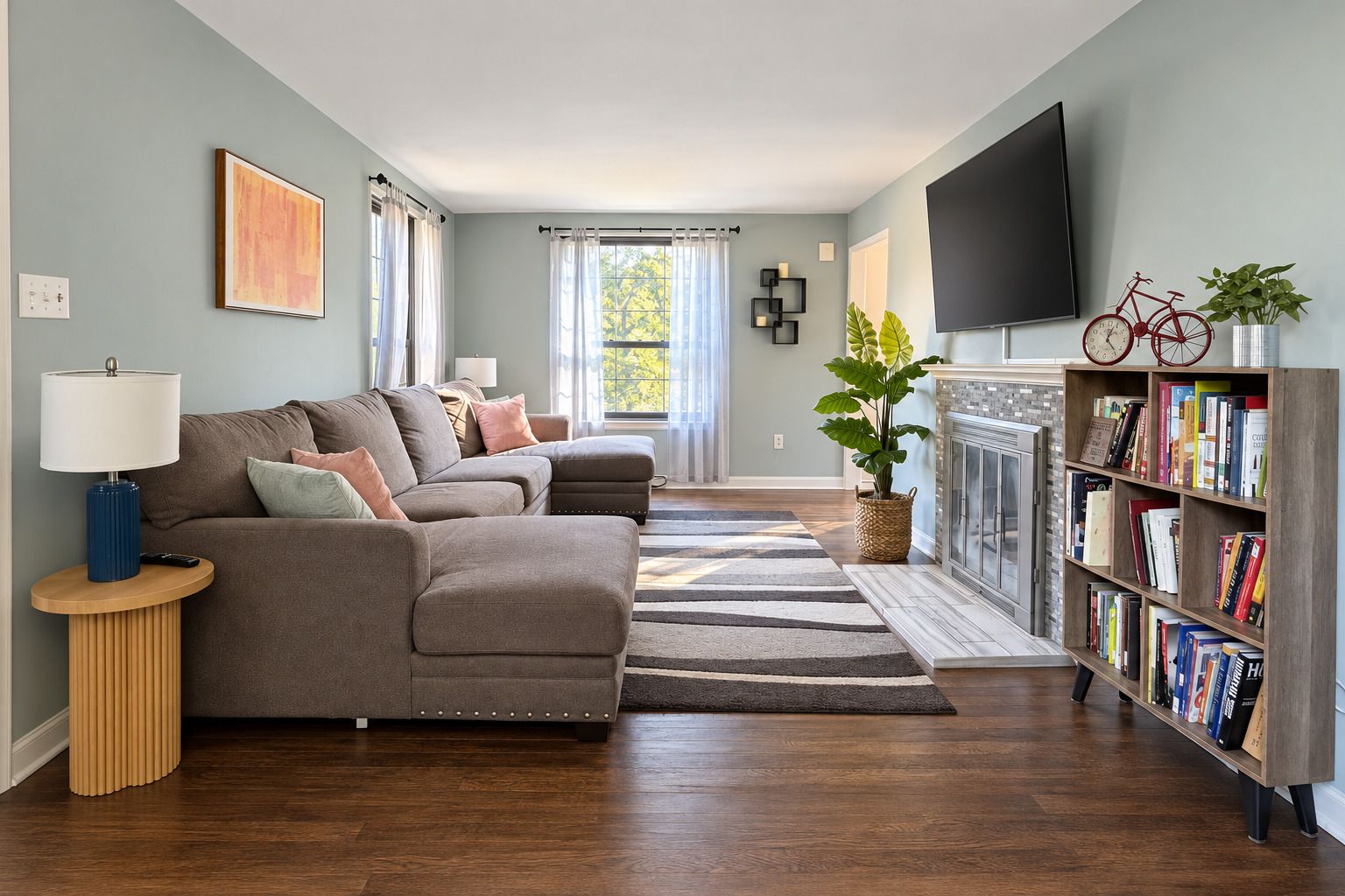A living room with a sectional sofa, a coffee table, a bookshelf, a fireplace, and a television.