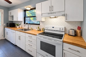 A modern kitchen with white cabinets, a stainless steel sink, a built-in oven, and a toaster.