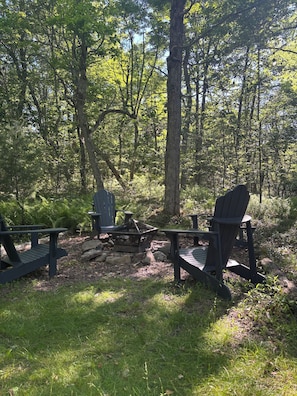 A forested campsite with Adirondack chairs and a fire pit. - Charming 4-Bedroom Cabin in Lake Harmony, PA PERFECT for your next getaway! (Lake Harmony)