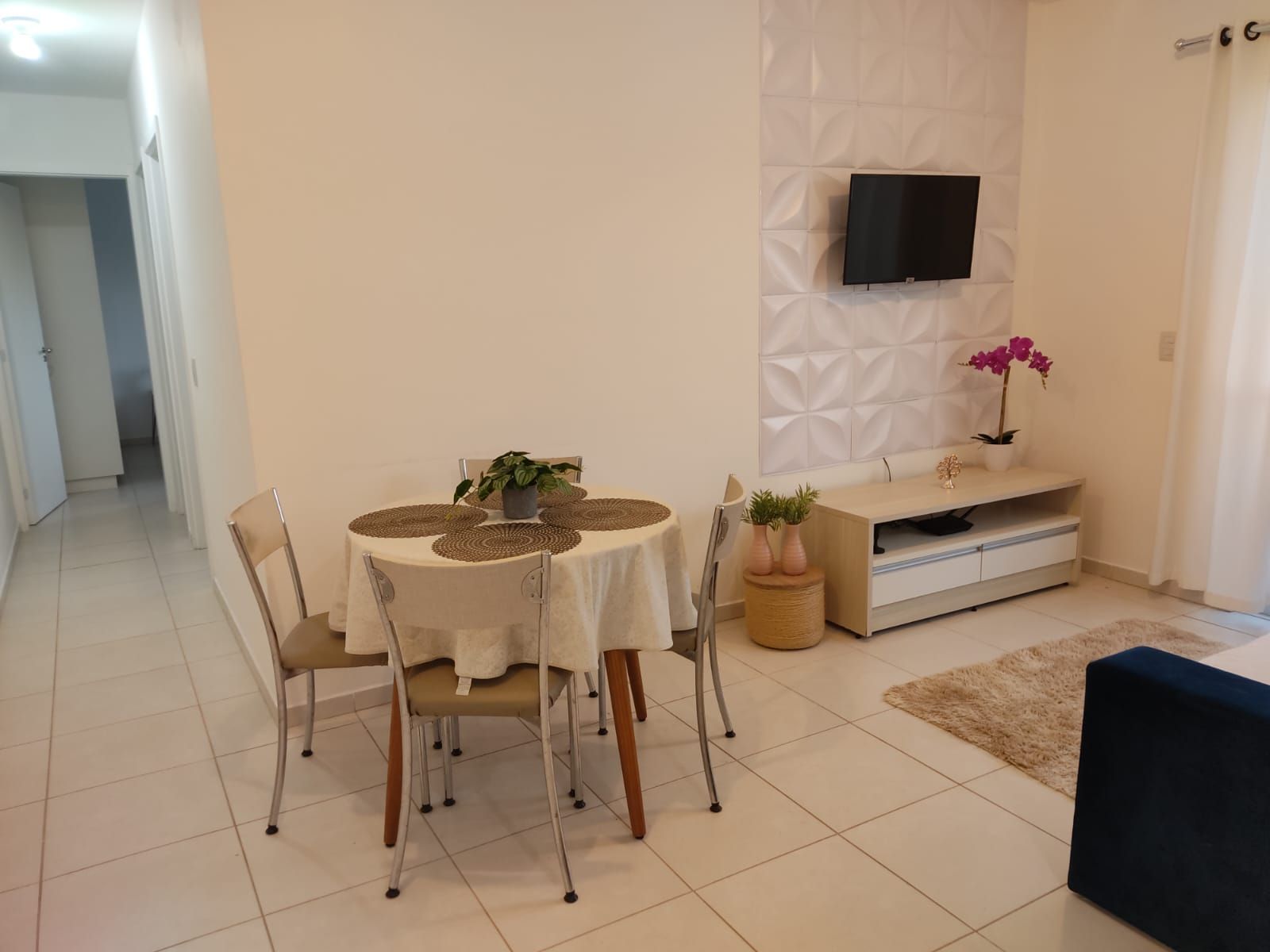 Un comedor con una mesa redonda, sillas y un televisor montado en la pared.