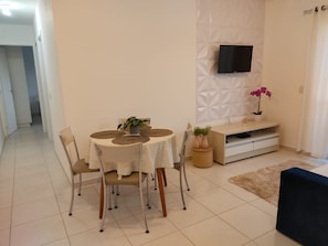 Un comedor con una mesa redonda, sillas y un televisor montado en la pared.