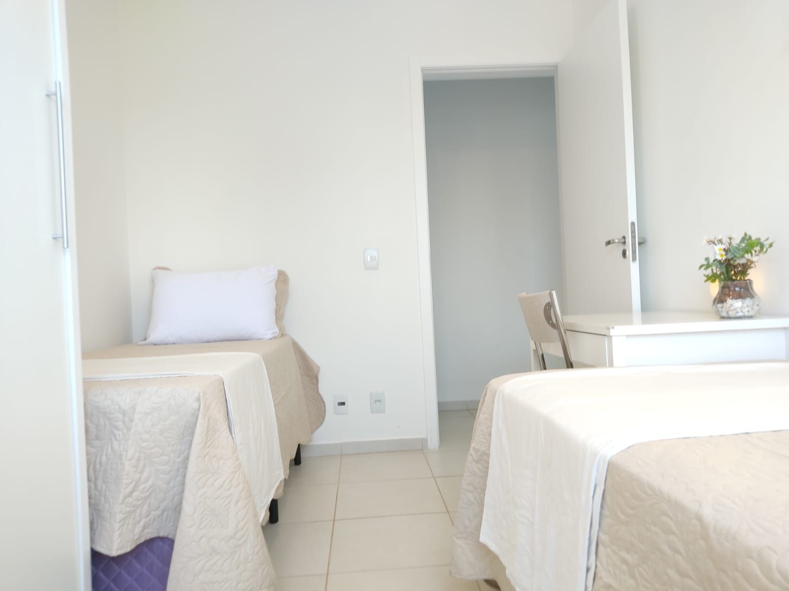 Un dormitorio con dos camas, una silla, un tocador y un espejo.