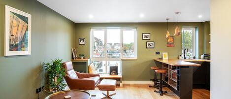A modern living room with a brown leather sofa, a round coffee table, and a view of a cityscape through large windows.