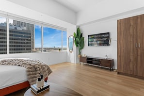Un dormitorio moderno con una cama grande, un aparador de madera, un espejo y vistas a la ciudad.