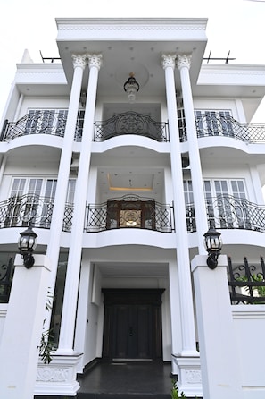 A multi-story building with a central entrance, large columns, and ornate balconies. - Suisse Luxury Residence (Nallur)