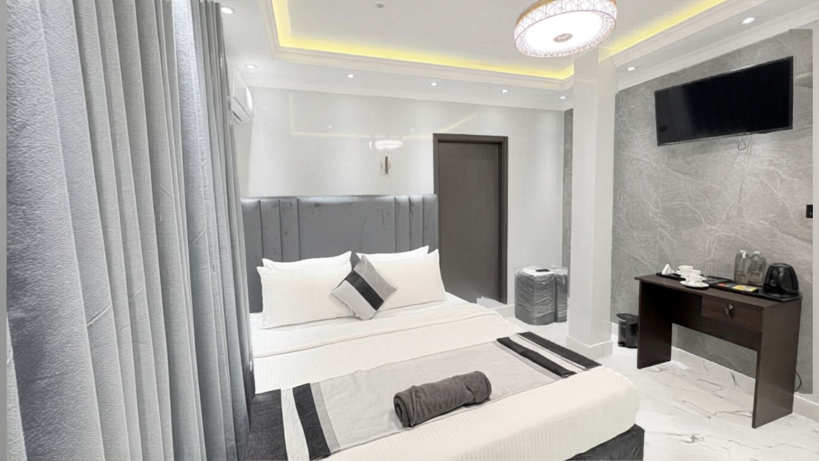 A modern bedroom with a bed, bedside table, and a TV mounted on the wall.