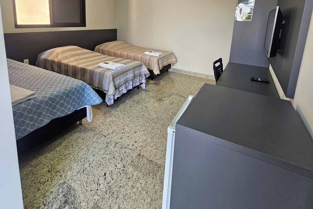 A hotel room with two beds, a TV, and a small table.