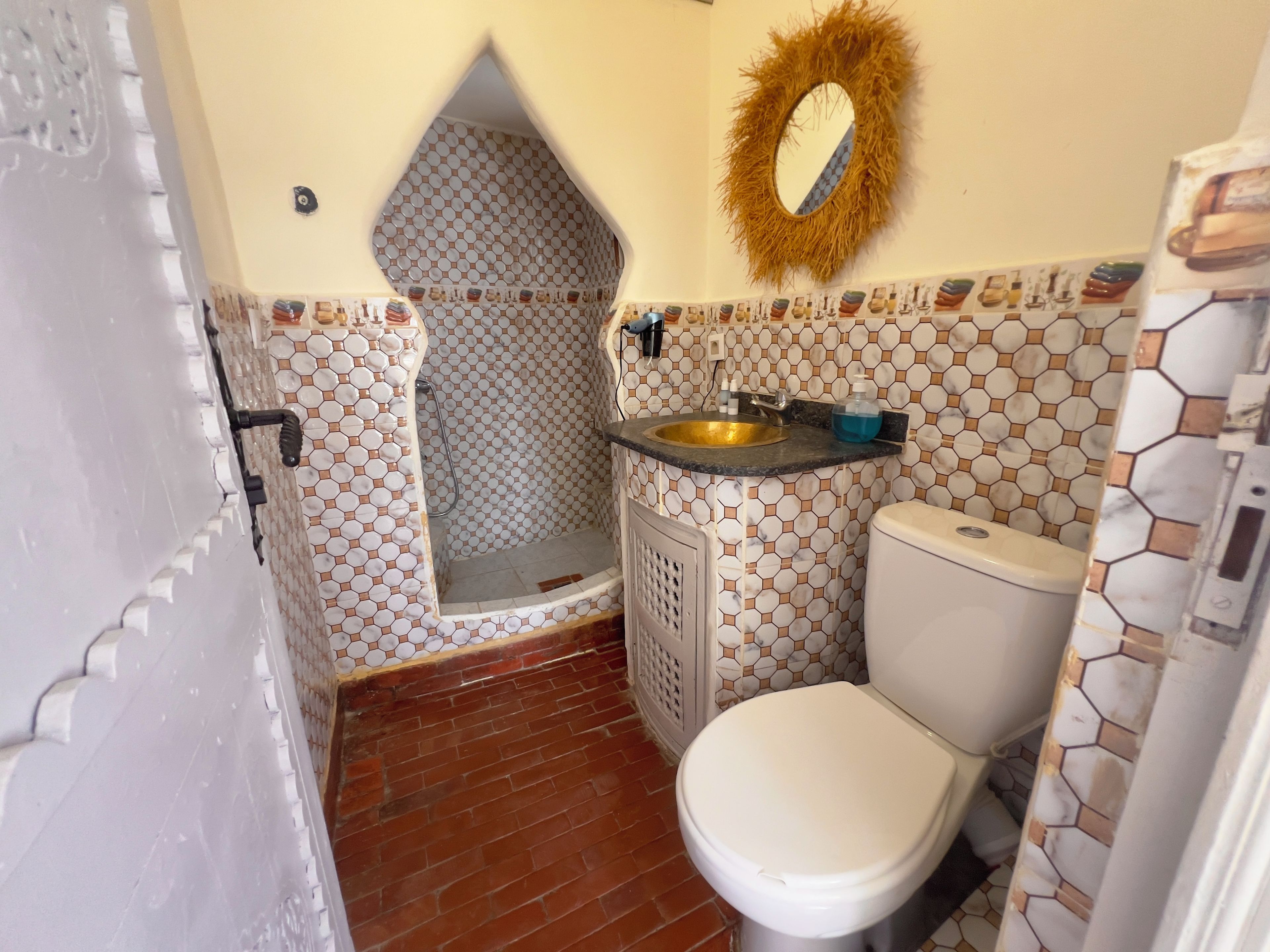 Une salle de bain avec douche, toilettes et lavabo.