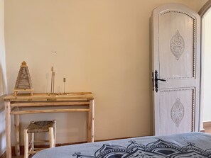 A room with a wooden desk, a woven chair, and a decorative door. - BLUE CITY (Chefchaouen)