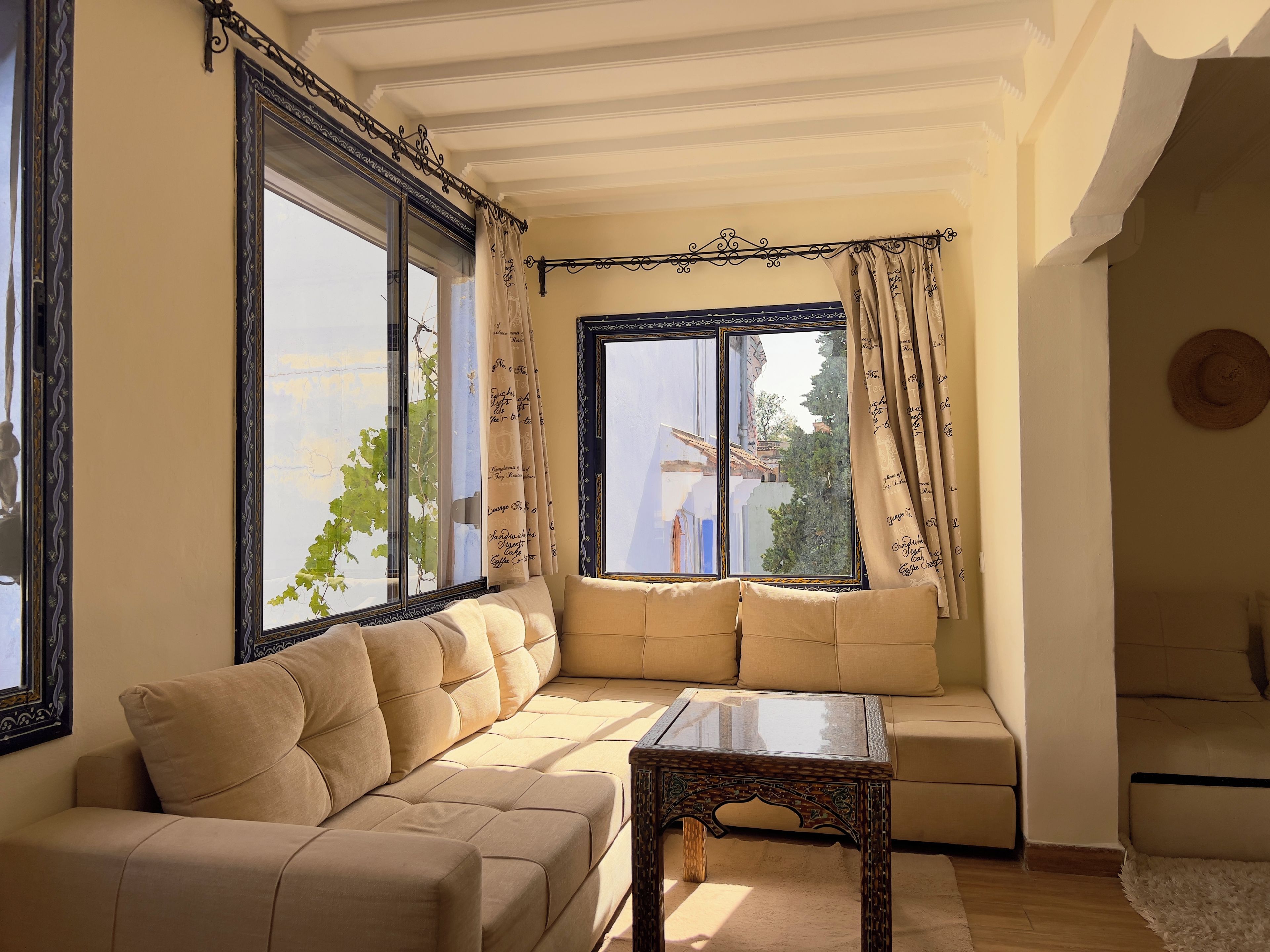 A living room with a sofa, a coffee table, and a large window with curtains.