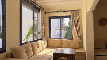 A living room with a sofa, a coffee table, and a large window with curtains.