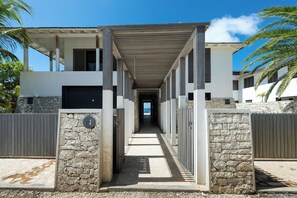 Passatge cobert que condueix a un edifici amb parets de pedra i vistes a la platja.