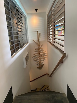 A narrow stairway with a wooden sculpture, a window with blinds, and a view of a colorful building outside. - New Listing (Kralendijk)