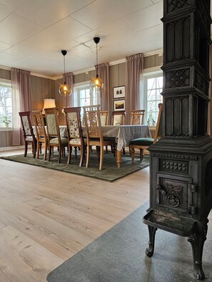 Un comedor con sillas de madera, una mesa y una estufa antigua.