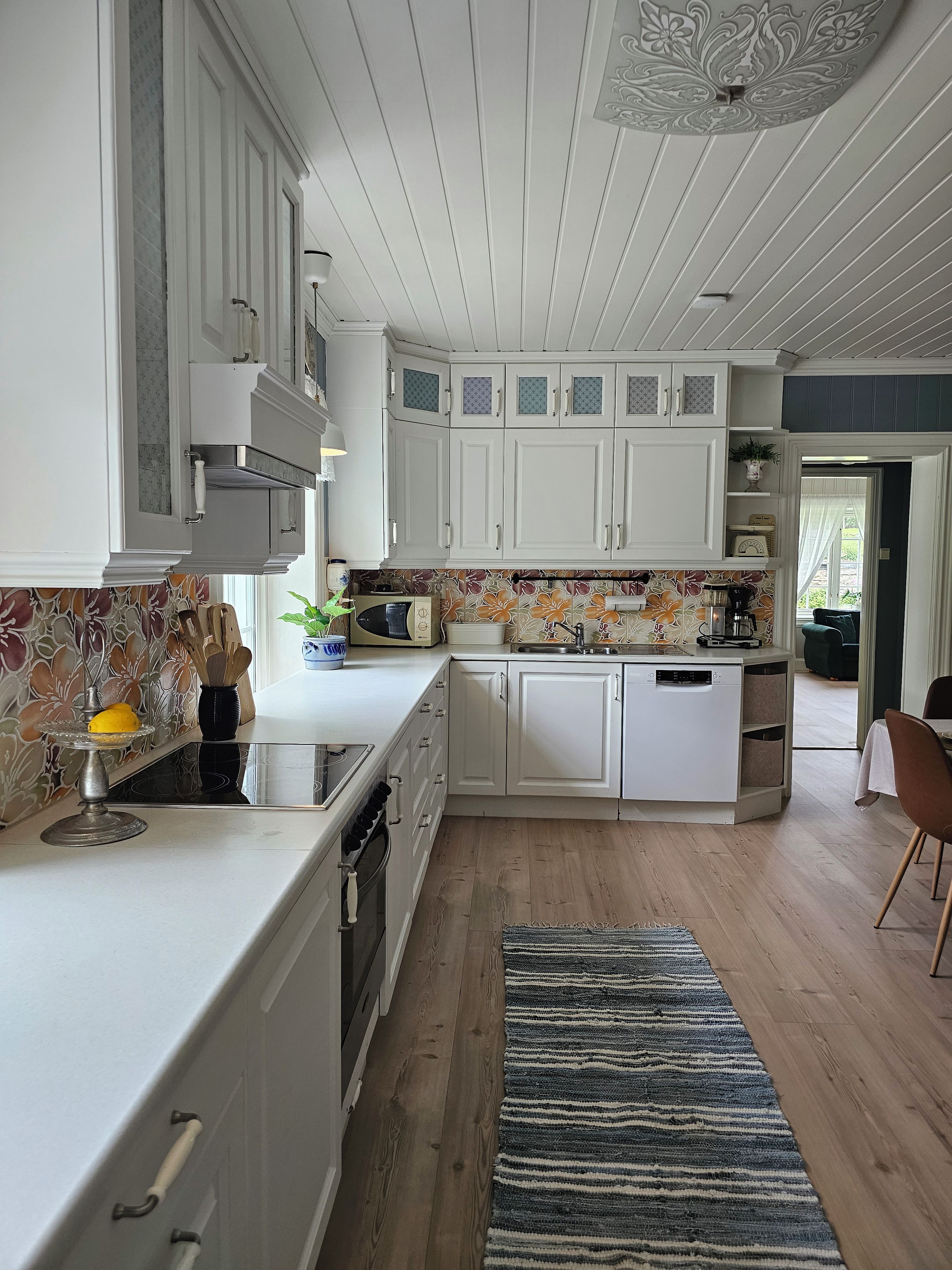 A modern kitchen with white cabinetry, a central island, and a patterned backsplash.