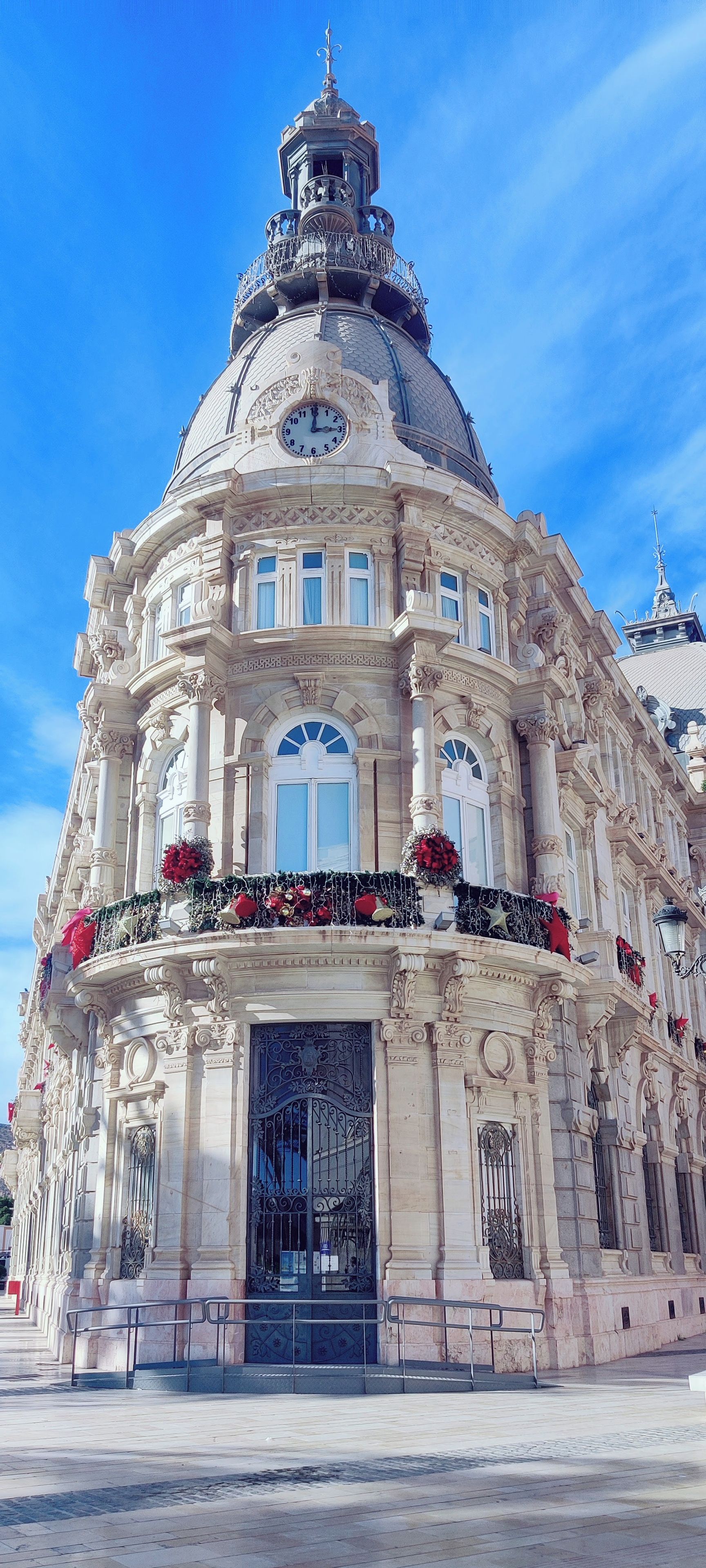 Un edificio histórico con una cúpula destacada, columnas ornamentadas y una entrada principal con un portón negro.