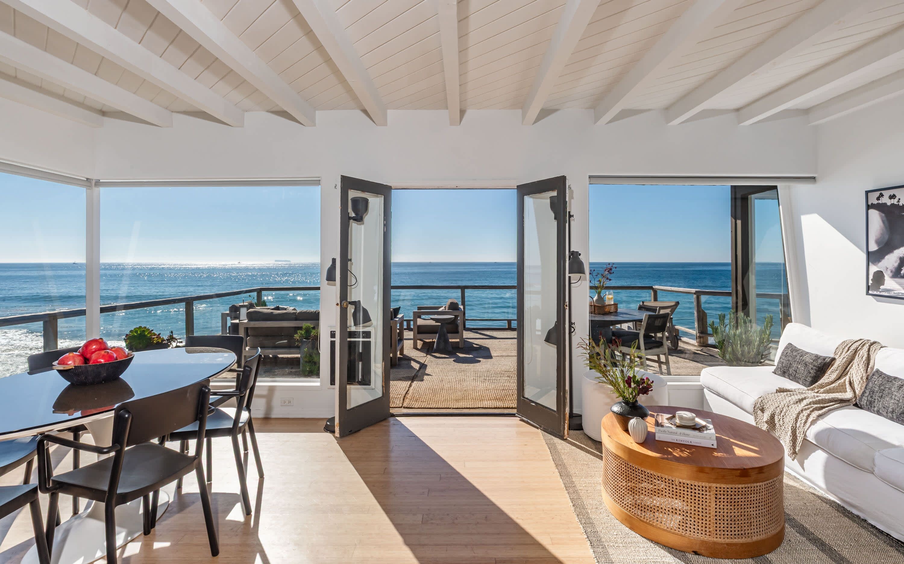 An open-plan living area with a view of the sea, a dining area with a table and chairs, and a seating area with a sofa and a coffee table.