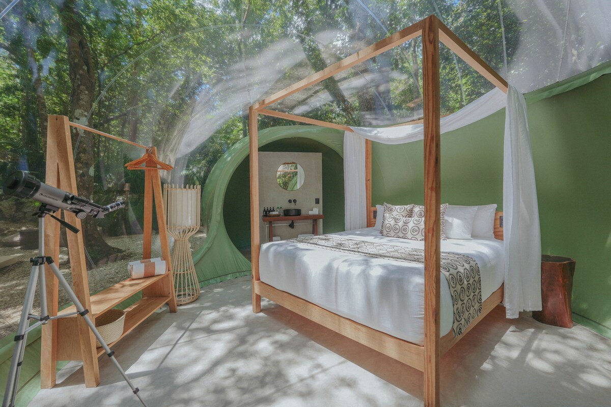 Un lit à baldaquin à quatre poteaux, avec un mur vert et une petite table placée à côté.