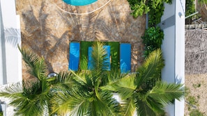 Una piscina con uno sfondo a muro in pietra, una porta blu e una rigogliosa vegetazione sul davanti.