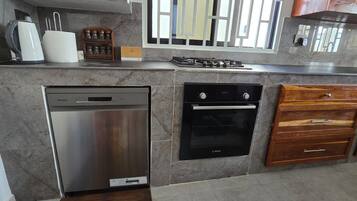 Una cucina con lavastoviglie Bosch, forno Bosch, mobili in legno e una finestra con persiane.