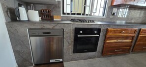 Una cucina con lavastoviglie Bosch, forno Bosch, mobili in legno e una finestra con persiane.