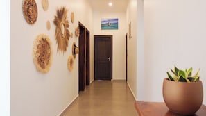 Un couloir doté d’un plancher en bois, d’une porte sombre et d’objets décoratifs fixés au mur.