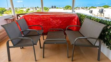 Una terrazza con un tavolo e due sedie rivestiti di rosso, con vista su una zona residenziale.