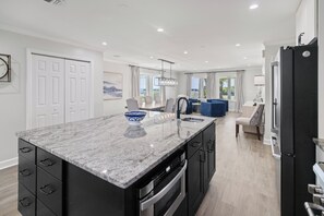 A modern kitchen with a marble countertop, built-in oven, and a large island. - Laguna Matata • 5BR • Private Pool • Gulf Views • Hot Tub (Panama City Beach)