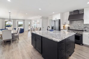 A modern kitchen with a large island, built-in appliances, and a dining area with a view. - Laguna Matata • 5BR • Private Pool • Gulf Views • Hot Tub (Panama City Beach)