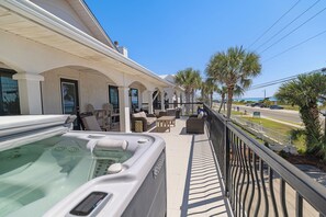 Un balcon d’hôtel avec un jacuzzi, des sièges d’extérieur et une vue sur l’océan.