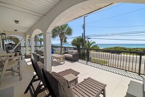 A covered outdoor seating area with tables and chairs, overlooking a beach and the ocean. - Laguna Matata • 5BR • Private Pool • Gulf Views • Hot Tub (Panama City Beach)