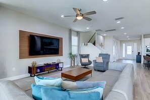 A modern living room with a flat-screen TV, a sofa, a coffee table, and a ceiling fan. - ECR7654 - Family Oasis Retreat + Spa + Theater! (Kissimmee)