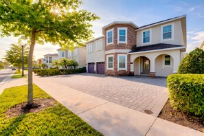 A residential street with modern houses, paved sidewalks, and well-maintained lawns. - ECR7654 - Family Oasis Retreat + Spa + Theater! (Kissimmee)