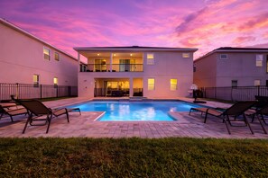 A two-story building with a swimming pool, lounge chairs, and a well-maintained lawn. - ECR7654 - Family Oasis Retreat + Spa + Theater! (Kissimmee)