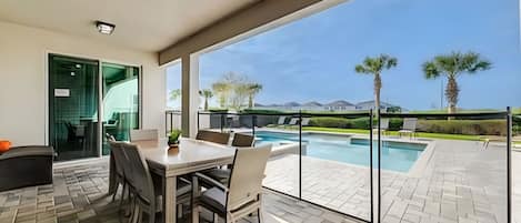 Un patio con mesa y sillas, piscina y vistas al paisaje.