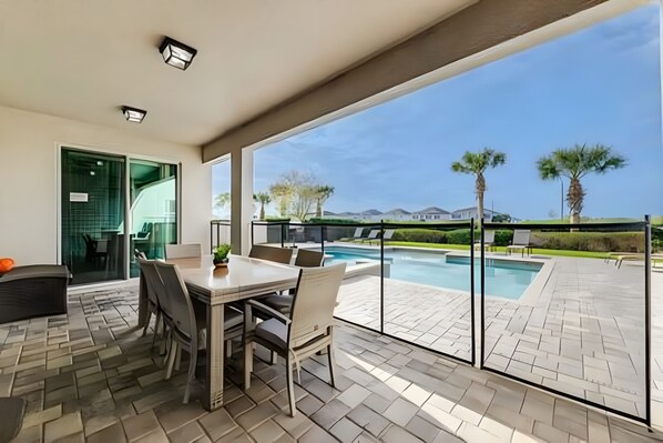 Eine Terrasse mit Esstisch und Stühlen, ein Schwimmbad und ein Blick auf die Landschaft.