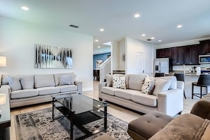 A modern living room with a sofa, coffee table, and a view of the kitchen. - ECR7537 - MagicVilla Retreat, Theater @Encore (Kissimmee)