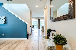 A modern interior with a blue accent wall, a staircase, and a reception desk with a plant. - ECR7537 - MagicVilla Retreat, Theater @Encore (Kissimmee)