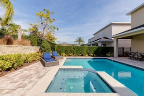 A swimming pool with lounge chairs and a hot tub, surrounded by a landscaped garden and a building. - ECR7391 - Family Luxury Retreat + Pool @Encore! (Kissimmee)
