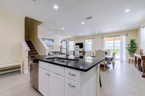 A spacious kitchen with a central island, a dining area with a table and chairs, and a staircase leading to another level. - ECR641 - Stunning Dream Vacation+Theater @Encore (Kissimmee)