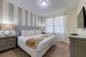 A hotel room with a bed, bedside tables, a mirror, a television, and a window with curtains. - ECR641 - Stunning Dream Vacation+Theater @Encore (Kissimmee)