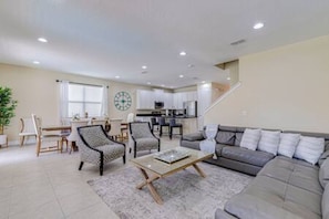 A modern living room with a grey sofa, patterned chairs, a coffee table, and a dining area with a table and chairs. - ECR641 - Stunning Dream Vacation+Theater @Encore (Kissimmee)