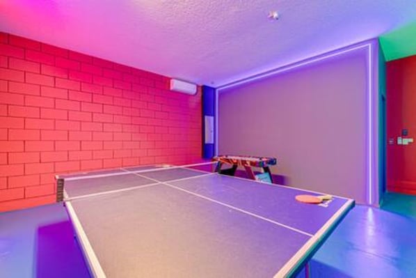 A ping pong table with a net in a room with red brick walls and a door. - ECR641 - Stunning Dream Vacation+Theater @Encore (Kissimmee)